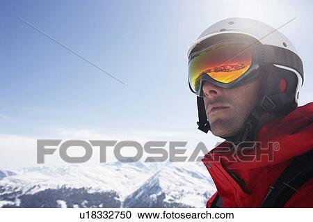 Stock Image - Austria, Saalbach, male skier wearing helmet and goggles, close-up. Fotosearch