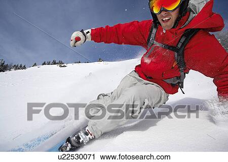 Stock Image - Austria, Saalbach, man skiing down mountain slope, smiling. Fotosearch