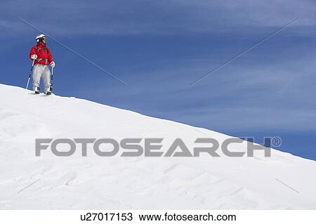 Stock Image - Male skier standing on snow covered slope. Fotosearch
