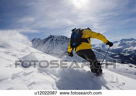Stock Photo - Male skiing on mountain, rear view. Fotosearch