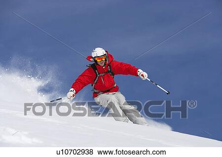 Stock Photo - Man skiing down snow covered slope, low angle view. Fotosearch
