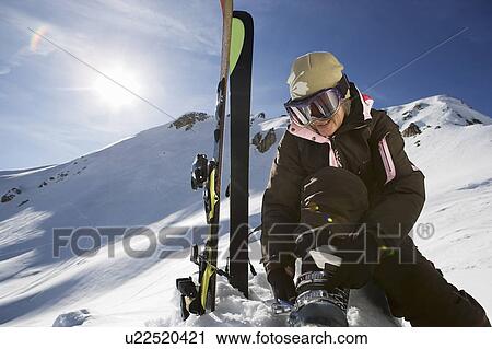 Mature female skier fastening boot bindings on mountain View Large Photo Image Stock Image - Mature female skier fastening boot bindings on mountain. Fotosearch