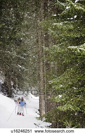Stock Image - Two young blonde women stand in forest in snow-shoes, portrait. Fotosearch
