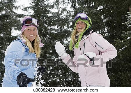 Two young blonde women wearing ski-wear throwing snowballs at camera in forest View Large Photo Image Stock Photo - Two young blonde women wearing ski-wear throwing snowballs at camera in forest. Fotosearch
