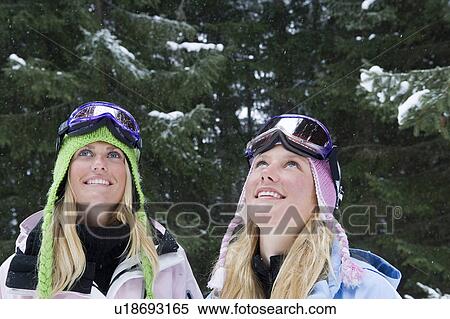 Stock Photography - Two young blonde women wearing ski-wear in forest. Fotosearch