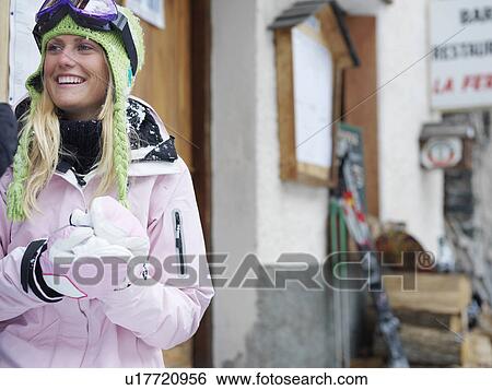 Stock Photograph - Young woman smiling, standing outside restaurant, portrait. Fotosearch