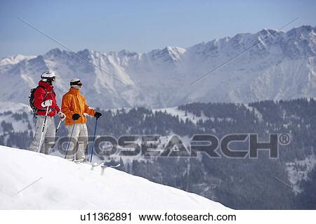 Austria, Saalbach, two male skiers on slope looking towards mountains View Large Photo Image Stock Image - Austria, Saalbach, two male skiers on slope looking towards mountains. Fotosearch