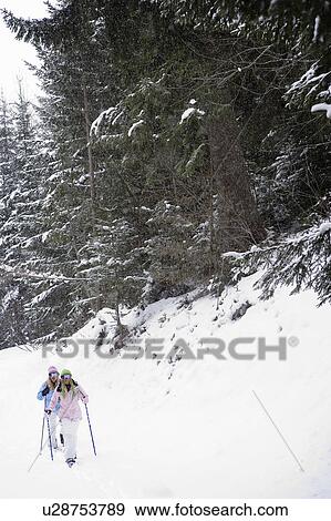 Two young blonde women walking down small hill in forest using snow-shoes View Large Photo Image Stock Photo - Two young blonde women walking down small hill in forest using snow-shoes. Fotosearch