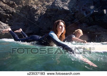 Couple lying on surfboards in the water smiling. View Large Photo Image Stock Image - Couple lying on surfboards in the water smiling.. Fotosearch