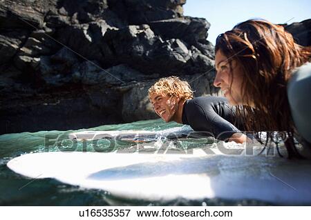 Couple lying on surfboards in the water smiling. View Large Photo Image Stock Photo - Couple lying on surfboards in the water smiling.. Fotosearch