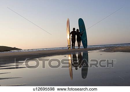 Couple standing on beach with surfboards. View Large Photo Image Stock Photo - Couple standing on beach with surfboards.. Fotosearch