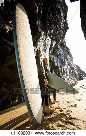 Couple standing with surfboards by large rocks smiling. View Large Photo Image Stock Photo - Couple standing with surfboards by large rocks smiling.. Fotosearch
