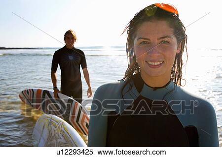 Stock Photography - Couple with surfboards on beach smiling.. Fotosearch