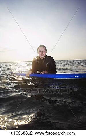 Stock Image - Female surfer floating in the surf.. Fotosearch