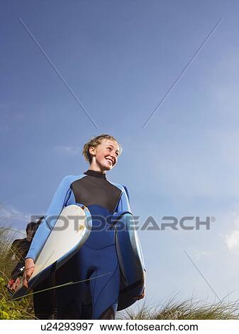 Stock Photo - Female surfer walking through grass.. Fotosearch