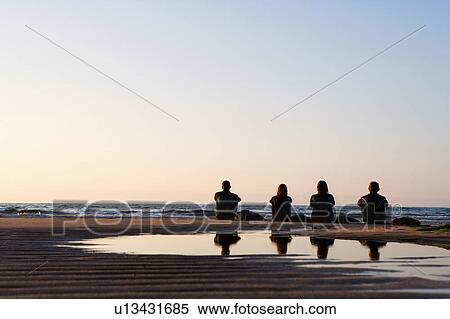Four people sitting on the beach with surfboards. View Large Photo Image Stock Photography - Four people sitting on the beach with surfboards.. Fotosearch