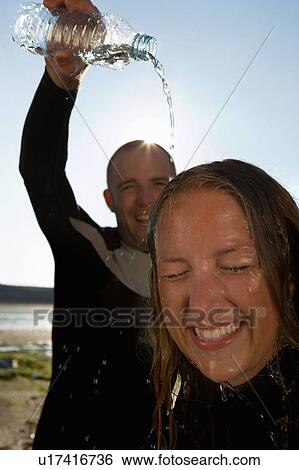 Stock Photograph - Laughing man pouring water over woman's head.. Fotosearch