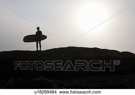 Picture - Man standing with surfboard.. Fotosearch