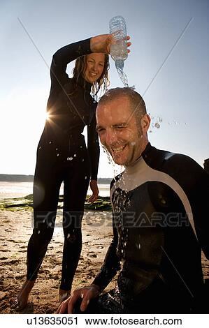 Woman pouring water over laughing man's head. View Large Photo Image Stock Image - Woman pouring water over laughing man's head.. Fotosearch