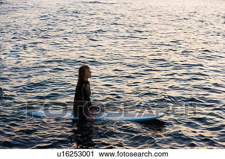 Woman sitting on surfboard in the water. View Large Photo Image Stock Image - Woman sitting on surfboard in the water.. Fotosearch
