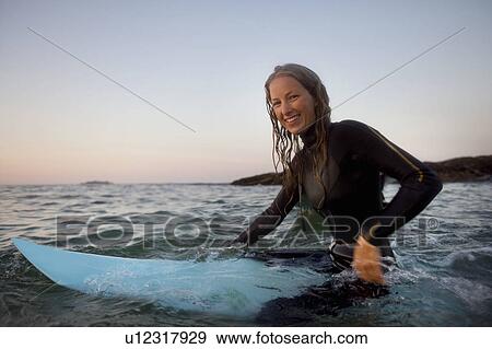 Woman sitting on surfboard in the water smiling. View Large Photo Image Stock Photo - Woman sitting on surfboard in the water smiling.. Fotosearch