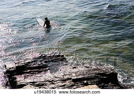 Stock Photography - Woman sitting on surfboard in the water.. Fotosearch