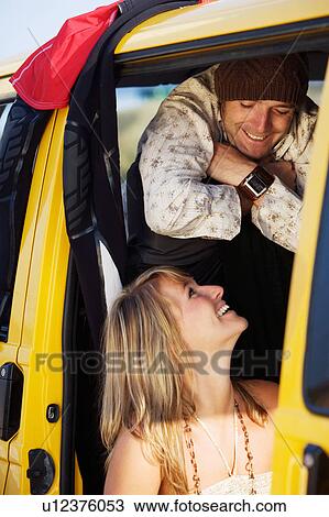 Stock Image - Couple in a van smiling at each other.. Fotosearch