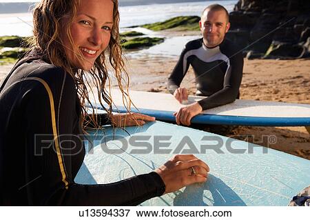 Couple waxing their surfboards smiling. View Large Photo Image Stock Photo - Couple waxing their surfboards smiling.. Fotosearch