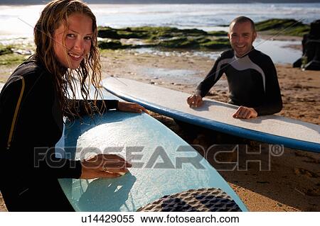 Couple waxing their surfboards smiling. View Large Photo Image Stock Photography - Couple waxing their surfboards smiling.. Fotosearch