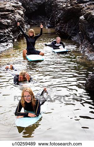 Four people having fun on surfboards in the water smiling. View Large Photo Image Stock Photo - Four people having fun on surfboards in the water smiling.. Fotosearch