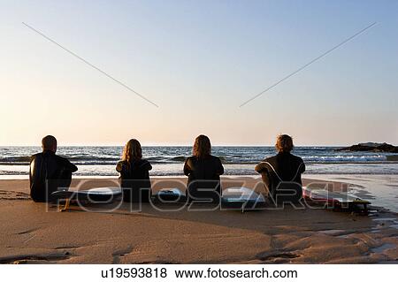 Four people sitting on the beach with surfboards. View Large Photo Image Stock Photo - Four people sitting on the beach with surfboards.. Fotosearch