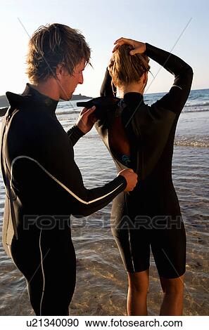 Man zipping up woman's wetsuit in shallow water. View Large Photo Image Stock Image - Man zipping up woman's wetsuit in shallow water.. Fotosearch