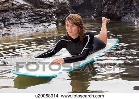 Woman lying on surfboard in the water. View Large Photo Image Picture - Woman lying on surfboard in the water.. Fotosearch