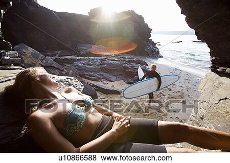 Woman relaxing with man carrying surfboards walking towards her smiling. View Large Photo Image Stock Photo - Woman relaxing with man carrying surfboards walking towards her smiling.. Fotosearch