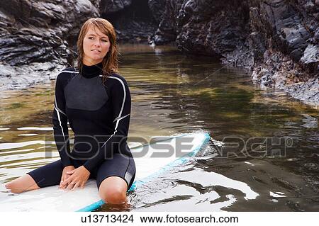 Woman sitting on surfboard in the water. View Large Photo Image Picture - Woman sitting on surfboard in the water.. Fotosearch