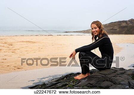 Woman sitting on the beach in wetsuit smiling. View Large Photo Image Stock Image - Woman sitting on the beach in wetsuit smiling.. Fotosearch