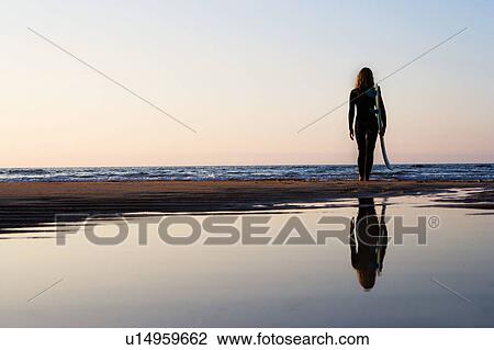 Woman standing on the beach holding surfboard. View Large Photo Image Stock Image - Woman standing on the beach holding surfboard.. Fotosearch