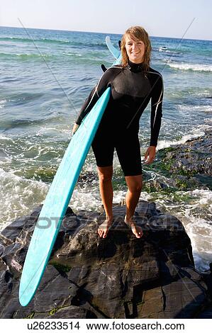 Woman standing with a surfboard smiling. View Large Photo Image Picture - Woman standing with a surfboard smiling.. Fotosearch