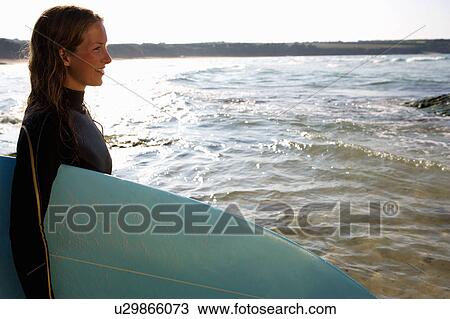 Woman standing with a surfboard smiling. View Large Photo Image Stock Image - Woman standing with a surfboard smiling.. Fotosearch