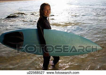 Woman standing with a surfboard smiling. View Large Photo Image Stock Photo - Woman standing with a surfboard smiling.. Fotosearch
