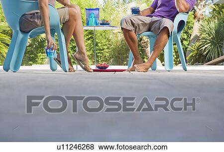 Stock Photo - Couple on a wooden terrace by a pool. Fotosearch