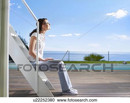 Female sitting outside with laptop View Large Photo Image Stock Image - Female sitting outside with laptop. Fotosearch