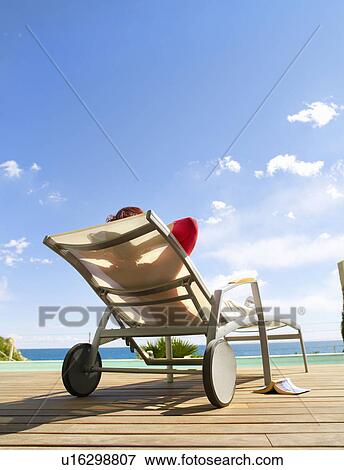 Mature woman relaxing on a deck chair View Large Photo Image Stock Photo - Mature woman relaxing on a deck chair. Fotosearch