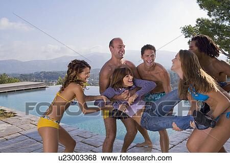 Stock Photo - Men and women throw a friend into a pool. Fotosearch