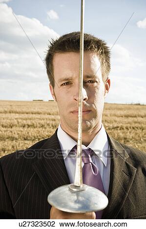 Stock Image - Businessman fencing in wheat field.. Fotosearch