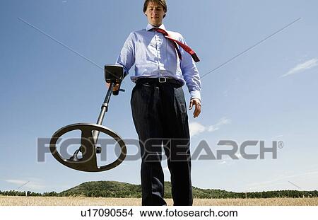 Picture - Businessman with metal detector outdoors.. Fotosearch