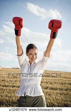 Picture - Businesswoman in wheat field wearing boxing gloves.. Fotosearch