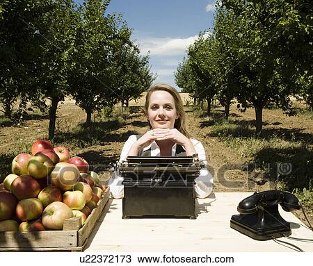 Woman sitting at desk in orchard. View Large Photo Image Stock Image - Woman sitting at desk in orchard.. Fotosearch