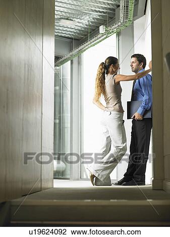 A woman talking to a man in a hallway View Large Photo Image Stock Image - A woman talking to a man in a hallway. Fotosearch