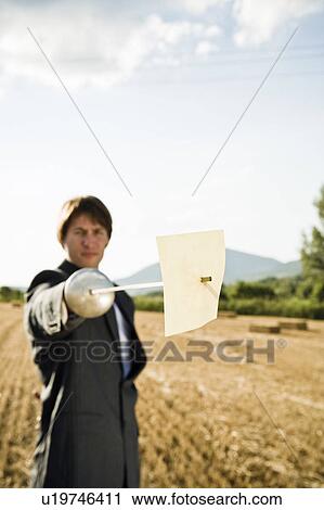 Stock Image - Businessman fencing in wheat field.. Fotosearch